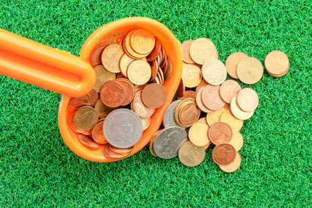coin in plastic spoon on green grass background with business conceptの写真素材