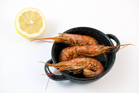 Three prawns in a pan on a white background
