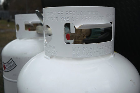 Two 20 twenty pound propane tanks attached to the front of an rv travel trailer. they are connected...