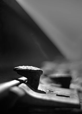 rail way spike black and white shot from low angle close up with rail track in background blurred out as it runs off into infinity.の写真素材
