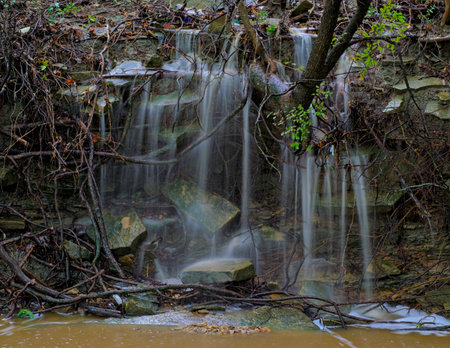 Storm caused waterfall flooding into small ditch with trash dammed up at top long exposure showing...