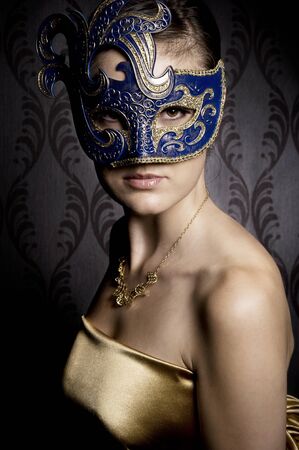 atractive woman in gold blue mask over wallpaper backgroundの写真素材