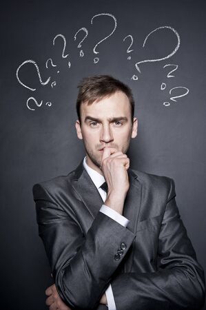 young handsome confused businessman with chalk drawn question marksの写真素材