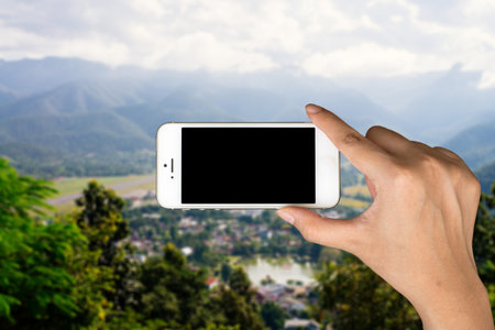 Phone in hand and blurred city in the backgroundの写真素材