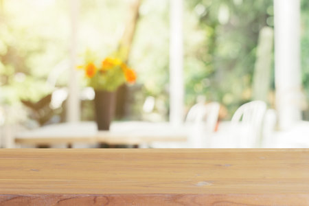 Wooden board empty table blurred background. Perspective brown wood over blur flower vase in coffee...