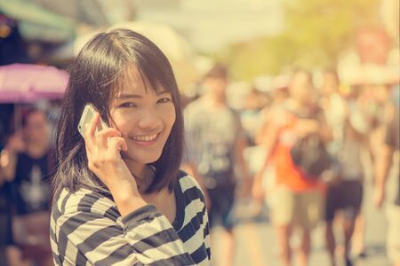 Happy woman smiling and walking in the street talking a smartphone and looking at camera. Vintage filtered image.の写真素材