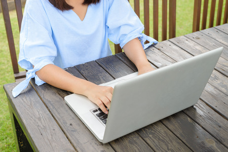 Happy casual beautiful woman watching videos or enjoying entertainment content in a laptop sitting in a coffee shop terrace outdoors in a sunny dayの写真素材