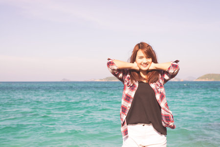 Woman relaxing at beach enjoying summer freedom with open arms and hair in the wind by the water seaside. Asian girl on summer travel holidays vacation outside. Vintage effect style pictures.の写真素材