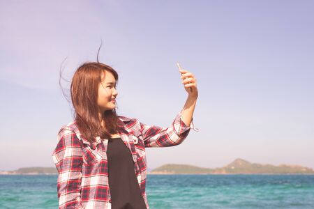 Blonde woman taking selfie using smartphone at sea travel lifestyle and modern technology concept.の写真素材
