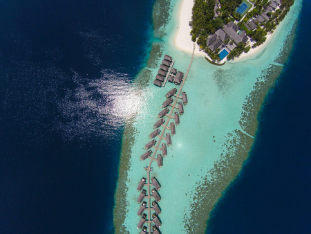 Aerial view of a tropical island in turquoise water. Luxurious over-water villas on tropical island resort maldives for holiday vacation background concept -Boost up color Processing.の写真素材