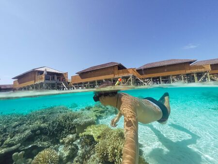 Young man snorkeling underwater on a colorful coral reef of Maldives island.の写真素材
