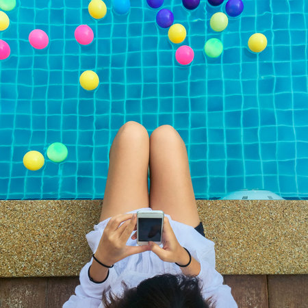 Beautiful young woman with beautiful smile reading good news on mobile phone  sitting by the...