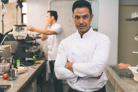 Smiling young asian chef in the kitchen interior.の写真素材