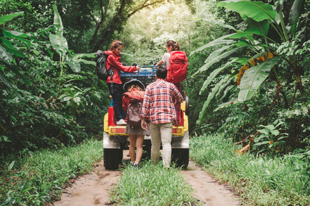 Happy asian young travellers with 4WD drive car off road in forest, young couple walking with backpacks and another two are enjoying on 4WD drive car. Young mixed race Asian woman and man.の写真素材