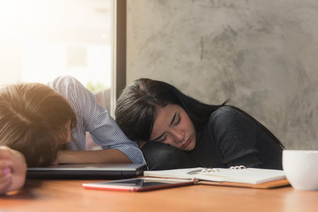Asian business woman in the office Tired overworked woman resting while she was working writing notes, overwork and stress concept.の写真素材