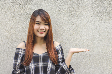 Close up portrait of happy young asian woman smiling and winking against gray  concrete wall. Vintage tone filter color style.の写真素材