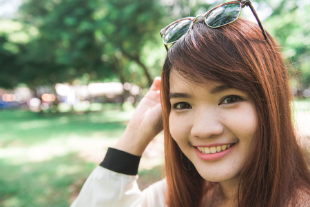 Calm beautiful smiling young woman with ponytail enjoying fresh air outdoor, relaxing with eyes closed, feeling alive, breathing, dreaming. Copy space, green park nature background. Side view portraitの写真素材