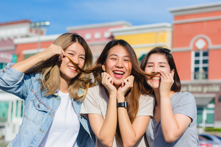 Happy young Asian women group city lifestyle playing and chatting each other among the pastel building city on weekend. City lifestyle of girls group. City lifestyle and outdoor activity concept.の写真素材