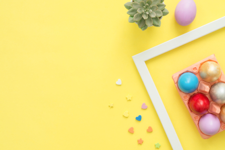 Flat lay top view colorful easter egg painted in pastel colors composition and spring flowers on yellow pastel color background. Easter day background top view with copy space.の写真素材