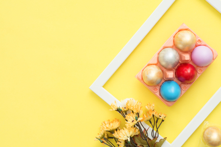 Flat lay top view colorful easter egg painted in pastel colors composition and spring flowers on yellow pastel color background. Easter day background top view with copy space.の写真素材