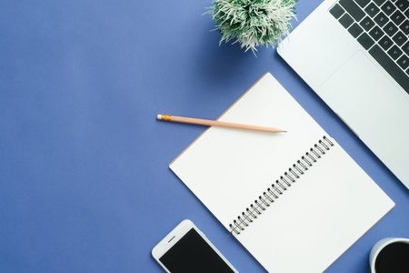 Office desk working space - Flat lay top view mockup photo of working space with laptop, smartphone, coffee up and notebook on blue pastel background. Pastel blue color background working desk conceptの写真素材
