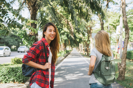 Couple of young Asian women standing along the street enjoying their city lifestyle on weekend waiting for outdoor activity. Young women and their city lifestyle. city lifestyle and outdoor concept.の写真素材