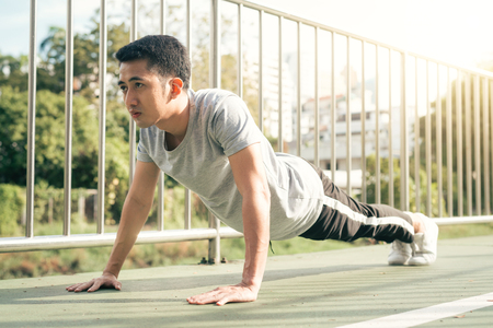 Fitness sport men fashion sportswear doing yoga fitness exercise in street. Fit young asian man doing training workout in morning. Young happy asian man stretching at park after running workout.の写真素材