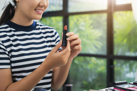 Beauty blogger present beauty cosmetics while sitting in front camera for recording video. Beautiful woman use lipstick while review make up tutorial broadcast live video to social network by internet.の写真素材