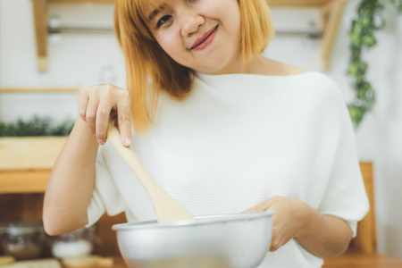 Asian woman making healthy food standing happy smiling in kitchen preparing salad. Beautiful cheerful Asian young woman at home. Healthy food dieting and healthy lifestyle cooking at home Concept.の写真素材