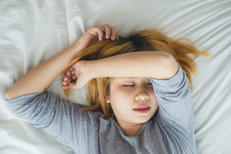 Beautiful young Asian woman sleeping in bed in the morning.の写真素材