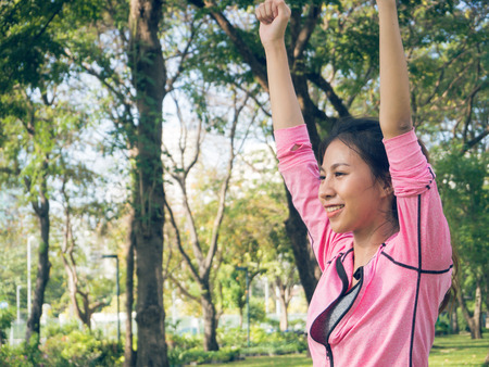 Asian young woman warm up the body stretching before morning exercise and yoga in the park under warm light morning. Healthy young asian woman exercising at park. Woman exercise outdoor concept.の写真素材