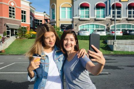 Attractive beautiful asian friends women using a smartphone. Happy young asian teenage at urban city...