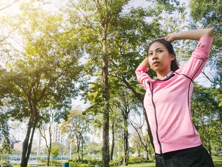 Asian young woman warm up the body stretching before morning exercise and yoga in the park under warm light morning. Healthy young asian woman exercising at park. Woman exercise outdoor concept.の写真素材