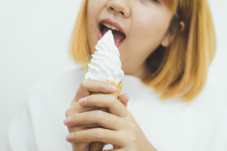 Indoor portrait of young beautiful asian woman eating ice cream in summer. Woman hands holding melting ice cream waffle cone. lifestyle asia woman conceptの写真素材