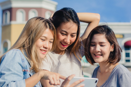 Attractive beautiful asian friends women using a smartphone. Happy young asian teenage at urban city while taking self portraits with her friends together with a smartphone.の写真素材