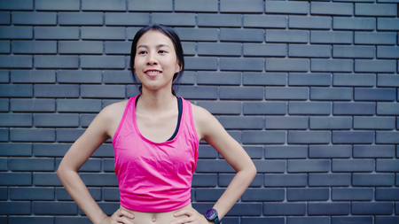 Healthy beautiful young Asian Athlete women in sports clothing legs warming and stretching her arms to ready for running on street in urban city. Lifestyle active women exercise in the city concept.の写真素材