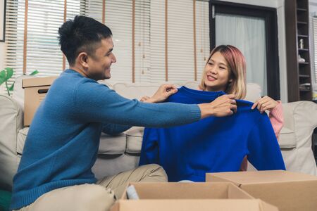 Young happy Asian couple moving to their new home, open boxes to check old objects from old home. Lifestyle couple move new home.の写真素材