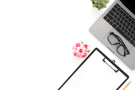 Creative flat lay photo of workspace desk. Top view office desk with laptop, glasses, pencil, blank clipboard and plant on white color background. Top view with copy space, flat lay photography.の写真素材