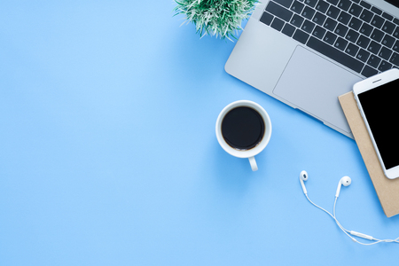 Office desk working space - Flat lay top view mockup photo of working space with laptop, smartphone, coffee up and notebook on blue pastel background. Pastel blue color background working desk conceptの写真素材