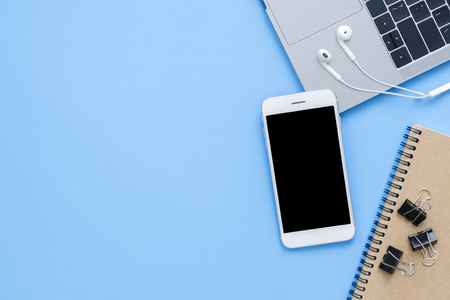 Office desk working space - Flat lay top view mockup photo of a working space with laptop, notebook, coffee and smartphone on blue pastel background. Pastel blue color copy space working desk concept.の写真素材