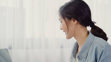 Beautiful smart Asian young entrepreneur business woman owner of SME online checking product on stock and save to computer working at home. Small business owner at home office concept.の写真素材