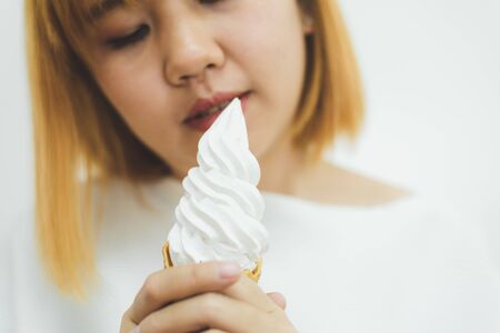Indoor portrait of young beautiful asian woman eating ice cream in summer. Woman hands holding melting ice cream waffle cone. lifestyle asia woman conceptの写真素材