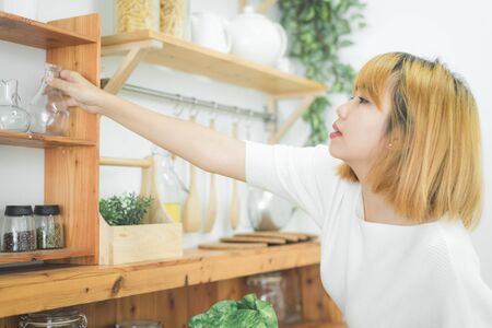 Asian woman making healthy food standing happy smiling in kitchen preparing salad. Beautiful cheerful Asian young woman at home. Healthy food dieting and healthy lifestyle cooking at home Concept.の写真素材