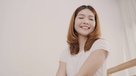 Beautiful young Asian woman traveler packing stuff in suitcase prepare for holiday vacation while lying on the bed when relax in her bedroom at home. Lifestyle women backpacker travel concept.の写真素材