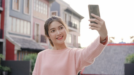 Cheerful beautiful young Asian backpacker blogger woman using smartphone taking selfie while traveling at Chinatown in Beijing, China. Lifestyle backpack tourist travel holiday concept.の写真素材
