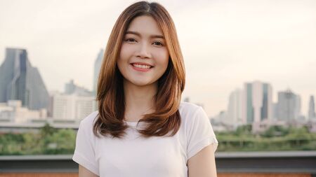 Cheerful beautiful young Asian woman feeling happy smiling to camera while traveling on the street at downtown city. Lifestyle backpack tourist travel holiday concept. Portrait looking at camera.の写真素材
