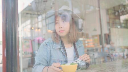 Business freelance Asian woman drinking warm cup of green tea or coffee while sitting on table in cafe. Lifestyle smart beautiful female relax in coffee shop concepts.の写真素材