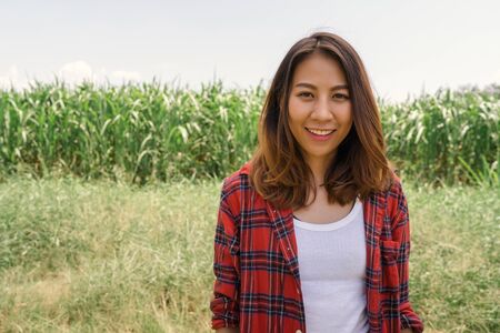 Cheerful asian female farmer and entrepreneur posing in the corn crop and smiling at camera, agriculture and cultivation concept.の写真素材