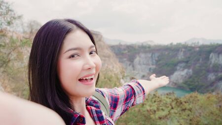 Blogger Asian backpacker woman record vlog video on top of mountain, young female happy using mobile phone make vlog video enjoy holidays on hiking adventure. Lifestyle women travel and relax concept.の写真素材