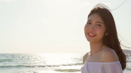 Young Asian woman walking on beach. Beautiful female happy relax walking on beach near sea when sunset in evening. Lifestyle women travel on beach concept.の写真素材